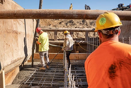 construction workers in ground hole with pipes